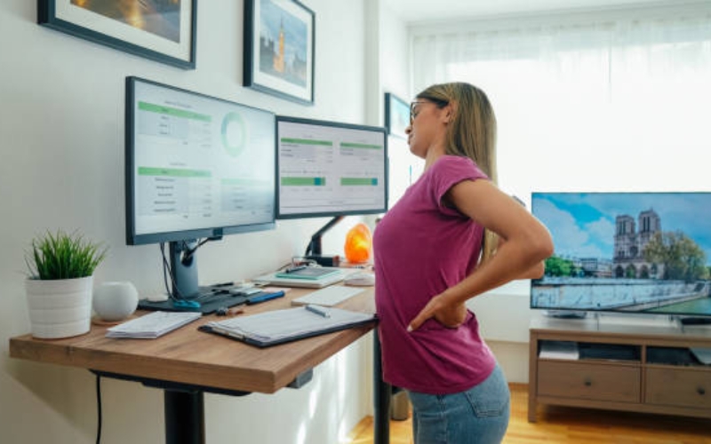 Woman with back pain working ata standing desk in a home office